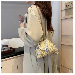 Dettaglio di borsa ricamata in stile cinese con elegante manico in perle sintetiche