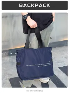 Primer plano de un bolso de nailon azul marino de gran capacidad sostenido por un modelo