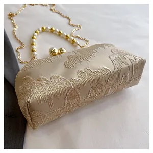 Detailed view of elegant champagne Chinese style clutch with embroidery and pearl handle