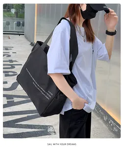 Bolso tote de nailon negro de gran capacidad en una modelo en un entorno urbano exterior