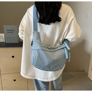 Detail view of a light blue canvas dumpling bag worn as a crossbody by a model