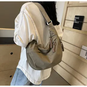 Close-up of khaki dumpling crossbody bag on model with woven strap detail