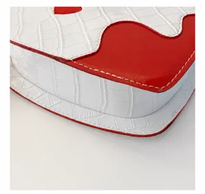 Detailed close-up of fine white stitching on a red and white crocodile texture heart bag