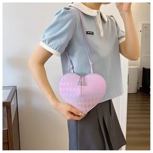 Detail einer pinkfarbenen, herzförmigen gesteppten Umhängetasche, getragen von einem Model.