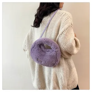 Vista trasera de una modelo con bolso bandolera de piel sintética violeta y suéter de punto crema