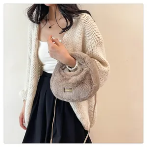 Vista detallada de un bolso bandolera de felpa beige suave con una etiqueta elegante.