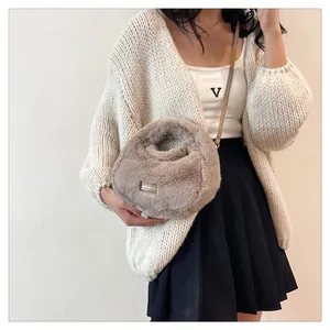 Bolso dumpling de piel sintética combinado con un elegante cárdigan de punto blanco.