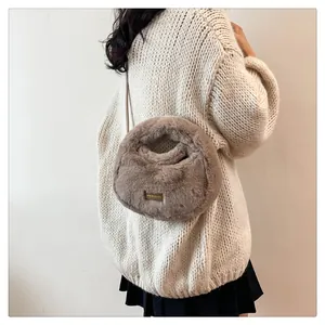 Primer plano de un bolso de peluche marrón sobre un suéter de punto beige
