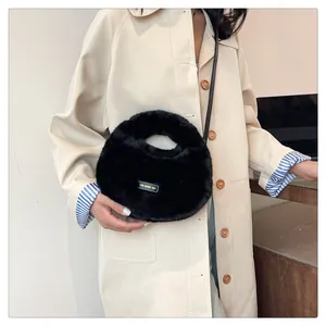 Lindo bolso de mano de felpa negra y bolso bandolera combinado con una gabardina beige