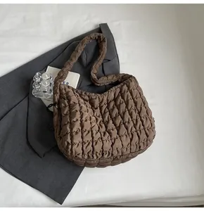 Detail view of a brown quilted bubble tote bag styled with a grey blazer.