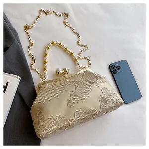 Detailed view of the champagne beaded clutch with fringe embroidery and pearl handle