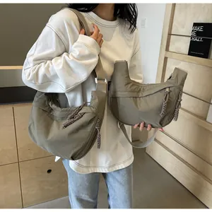 Detailed view showing two sizes of casual khaki nylon dumpling crossbody bags on model