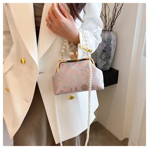 Dettaglio di una pochette ricamata rosa in stile cinese con eleganti cinturini di perle.