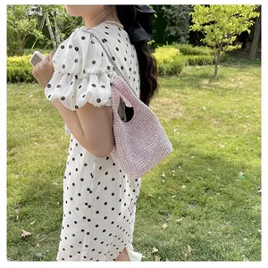 Elegant pink rhinestone bucket bag with chain strap shown in an outdoor lifestyle setting