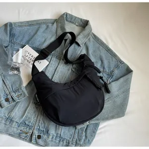 Detail view of a black canvas dumpling crossbody bag on a denim jacket background.