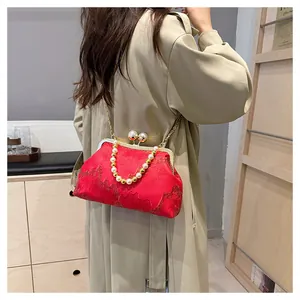 Close-up view of a red Chinese style jacquard clutch bag with pearl beaded handle