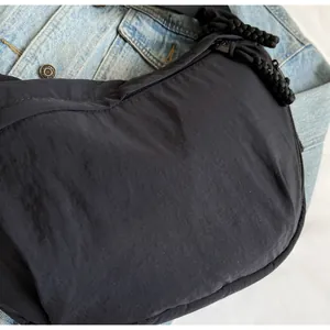 Close-up detail of black nylon dumpling crossbody bag featuring textured fabric and zipper