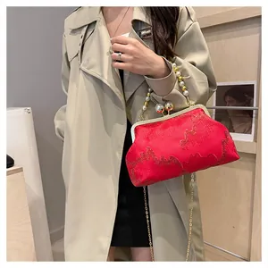 Model carrying a vibrant red New Chinese style handbag with pearl bead handles 2024.