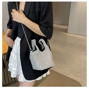 Detail view of a silver rhinestone bucket bag with chain strap worn with black blazer