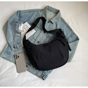 Large capacity black dumpling crossbody bag styled with denim jacket in a flat lay