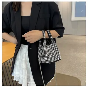Fashionable women's rhinestone bucket bag with chain strap shown on model.