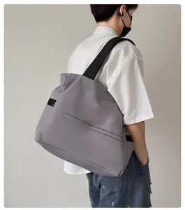 Vista lateral de un bolso de hombro de nailon gris puesto, destaca su gran capacidad