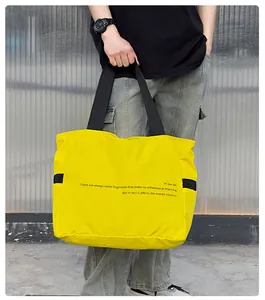 Bolso tote de nailon amarillo informal de gran capacidad sostenido por una persona