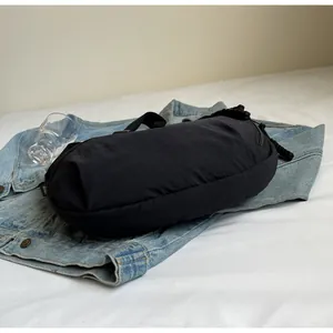 Side view of a black canvas dumpling bag on a denim jacket for a casual lifestyle look.