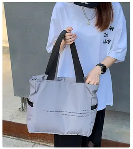 Detalle de un bolso de hombro de nailon gris con correa negra en estilo urbano casual
