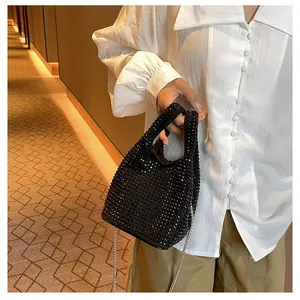 Elegant black rhinestone bucket bag with silver chain strap held by model.