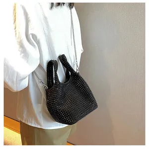 Elegant black rhinestone bucket bag with chain strap worn by a model in a detail view.