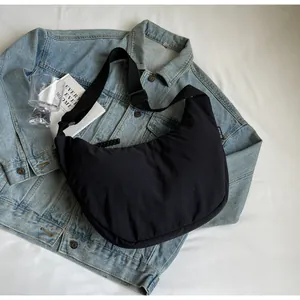 Large capacity black casual dumpling crossbody bag laid flat on a denim jacket