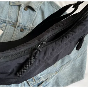 Close-up detail of black canvas dumpling bag with zipper and braided rope pulls