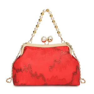Close-up of red sequined handbag featuring beaded pearl handle and elegant golden clasp