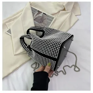 Detailed view of women's black bucket bag with silver rhinestones and chain strap