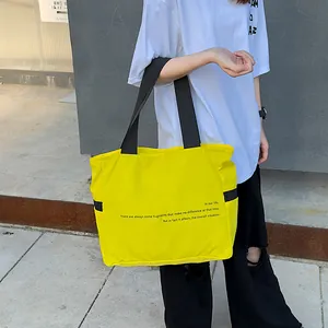 Bolso tote de nailon amarillo con correas negras en contraste y detalle de texto