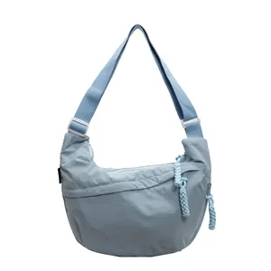 Detail view of light blue dumpling crossbody bag with braided rope zipper pull