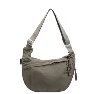 Stylish khaki crescent crossbody bag with adjustable strap and unique woven zipper pull