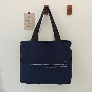 Vista detallada del bolso tote de nylon azul marino destacando el estampado blanco