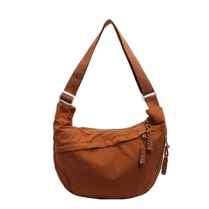 Front detail view of a brown casual dumpling crossbody bag with braided rope zipper pulls