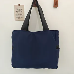 Vista completa del bolso tote de nailon azul marino colgado de un gancho de madera