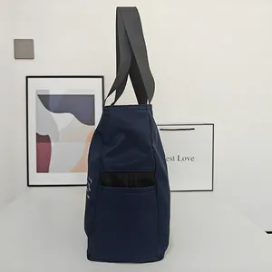 Vista lateral del bolso tote grande de nailon azul marino con bolsillo lateral de malla