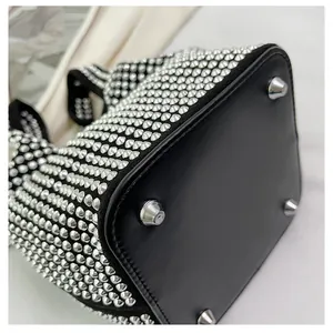 Close-up macro detail of shiny rhinestone bucket bag featuring black base and metal feet