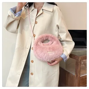 Primer plano de un bolso bandolera de peluche rosa llevado con una gabardina beige