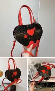 Close-up detail of the black crocodile textured heart-shaped handbag with red accents