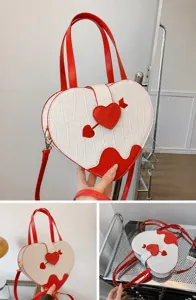 Detail of off-white heart-shaped crossbody bag with crocodile texture and red heart accent
