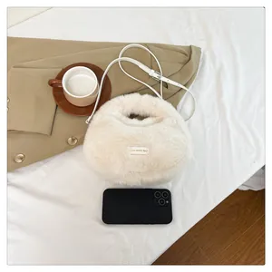 Detalle del bolso bandolera de peluche beige con teléfono para referencia de tamaño