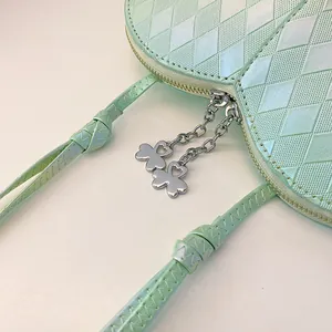Detailansicht der minzgrünen herzförmigen Tasche mit Rautenmuster und Kleeblatt-Zippern