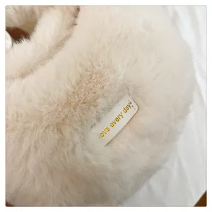 Detalle en primer plano de bolso de peluche suave con etiqueta dorada 'love every day' chic