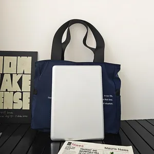 Bolso tote grande de nailon azul con tableta para comparar el tamaño